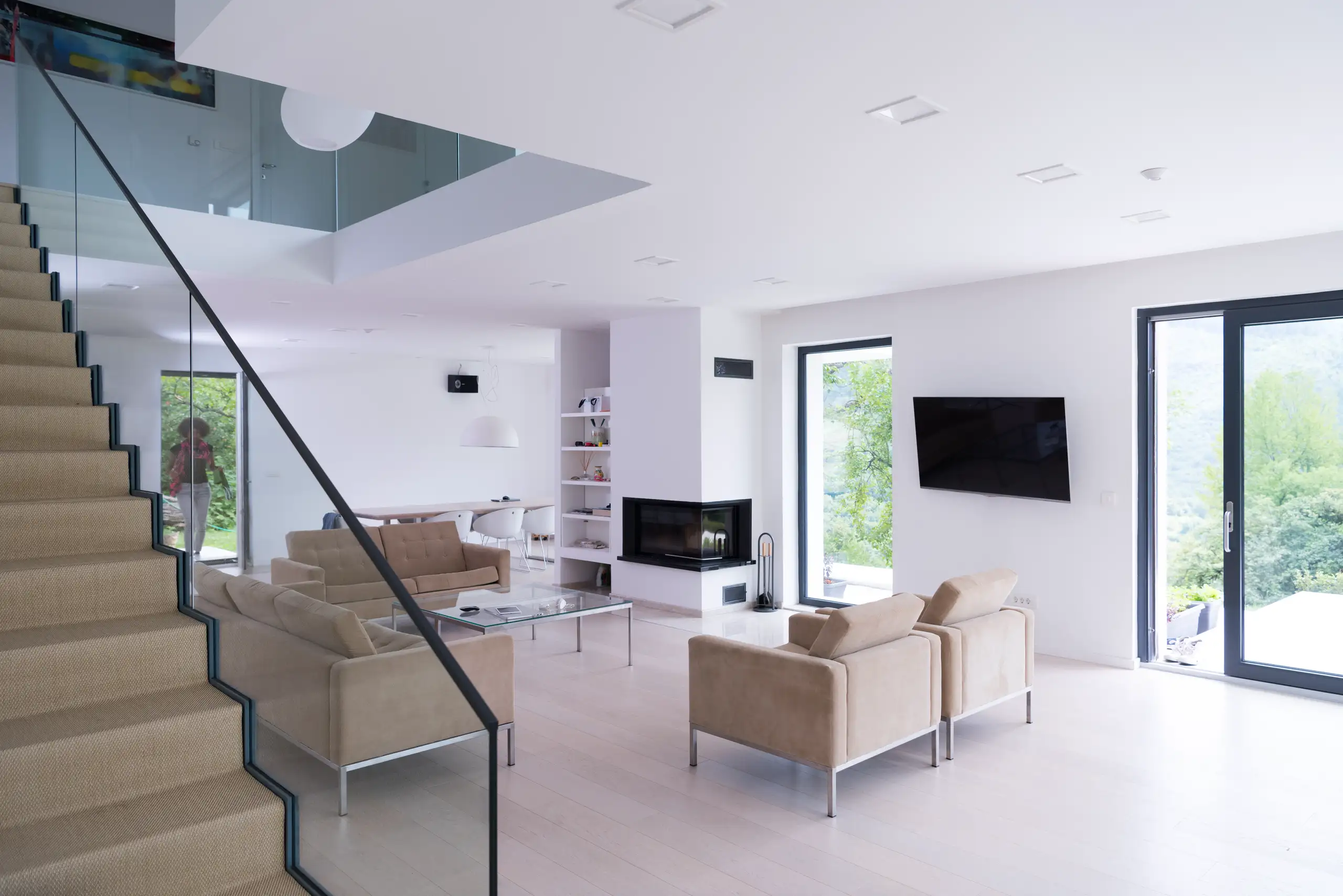 Balustrady szklane przy schodach w jasnym, minimalistycznym salonie z dużymi przeszkleniami