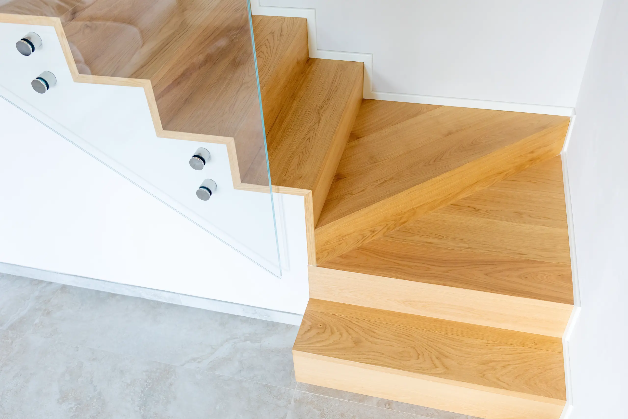 Drewniane schody policzkowe z przeszkloną balustradą i minimalistycznym wykończeniem